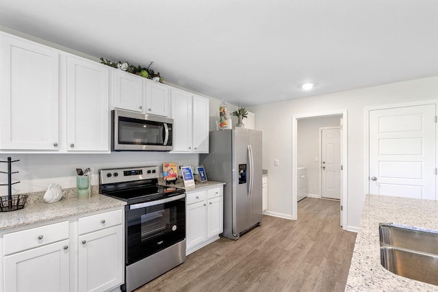 kitchen featuring stainless steel appliances, white cabinetry, light wood-type flooring, and light stone counters