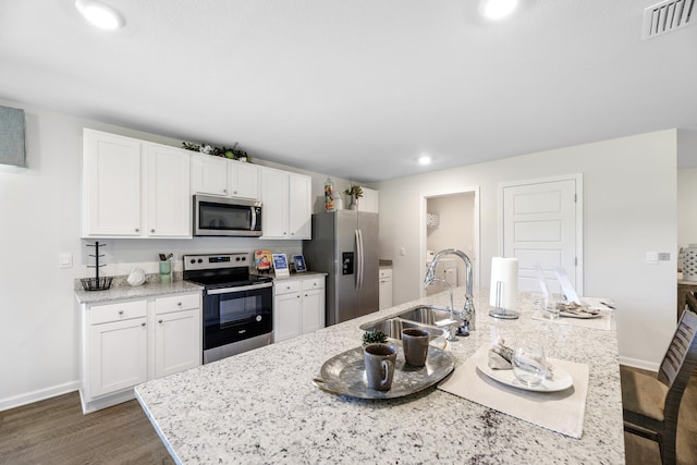 kitchen featuring dark hardwood / wood-style flooring, appliances with stainless steel finishes, sink, and a center island with sink