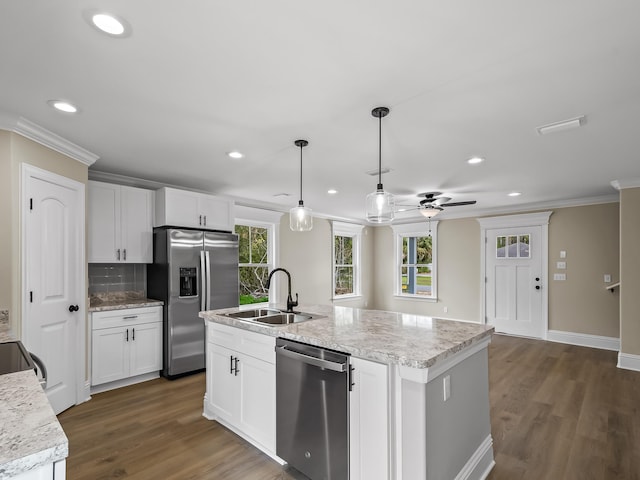 kitchen with hanging light fixtures, a kitchen island with sink, white cabinetry, and stainless steel appliances