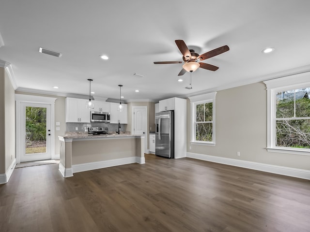 kitchen featuring appliances with stainless steel finishes, white cabinetry, an island with sink, hanging light fixtures, and dark hardwood / wood-style floors