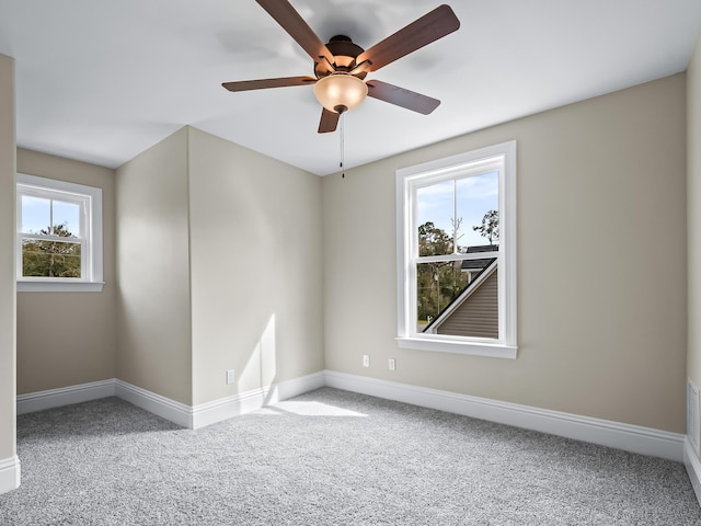 empty room with ceiling fan, a wealth of natural light, and light carpet