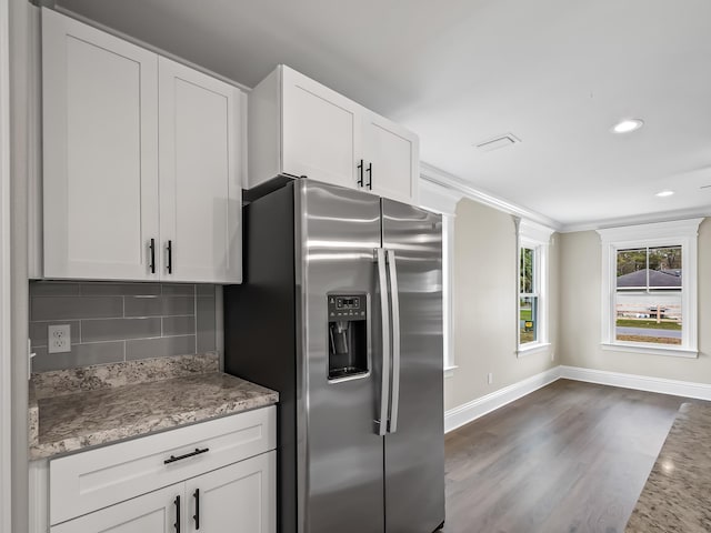 kitchen with white cabinets, backsplash, light stone counters, and stainless steel fridge