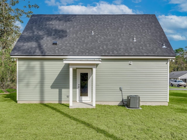 back of house with central AC unit and a lawn