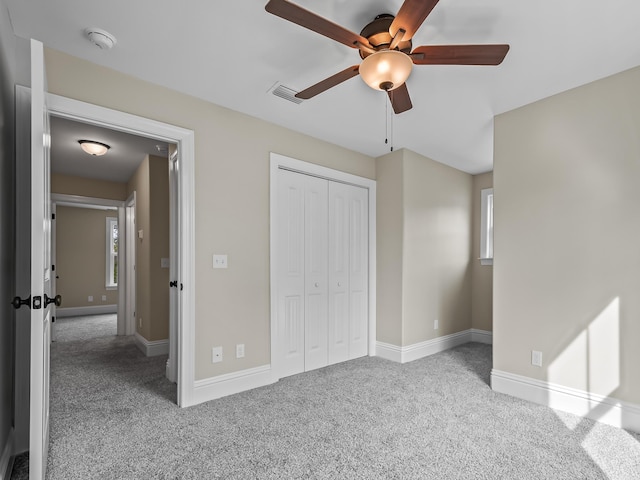 unfurnished bedroom featuring ceiling fan, light colored carpet, and a closet