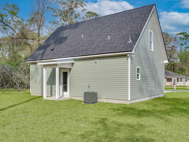 back of property with central air condition unit and a lawn