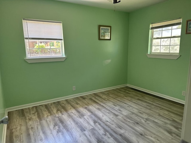 empty room with baseboards, wood finished floors, and plenty of natural light