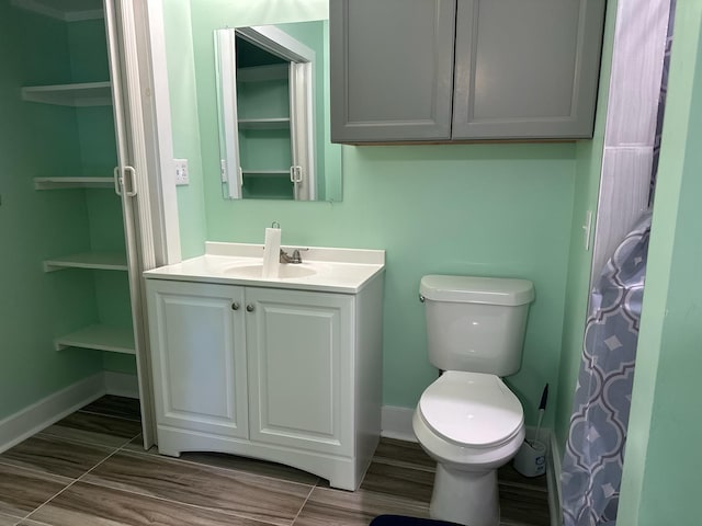 bathroom with baseboards, wood finished floors, toilet, and vanity