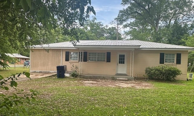 rear view of house with metal roof and a lawn