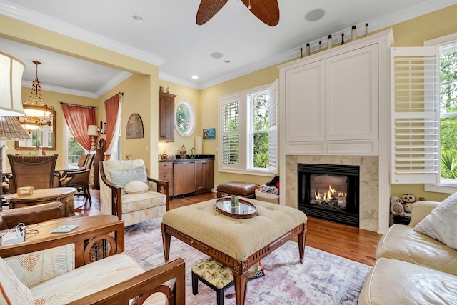 living room with a wealth of natural light, ceiling fan, crown molding, and light hardwood / wood-style flooring