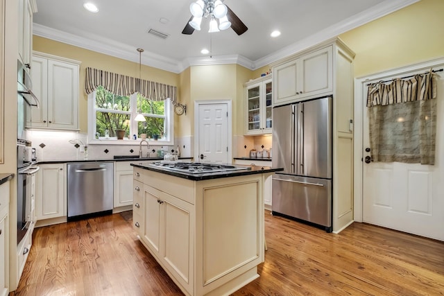 kitchen featuring crown molding, appliances with stainless steel finishes, a kitchen island, and light hardwood / wood-style flooring