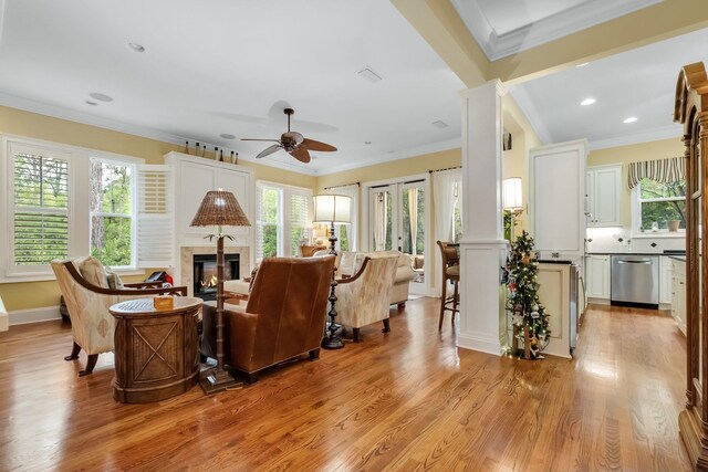 living room featuring light hardwood / wood-style flooring, ceiling fan, crown molding, and decorative columns