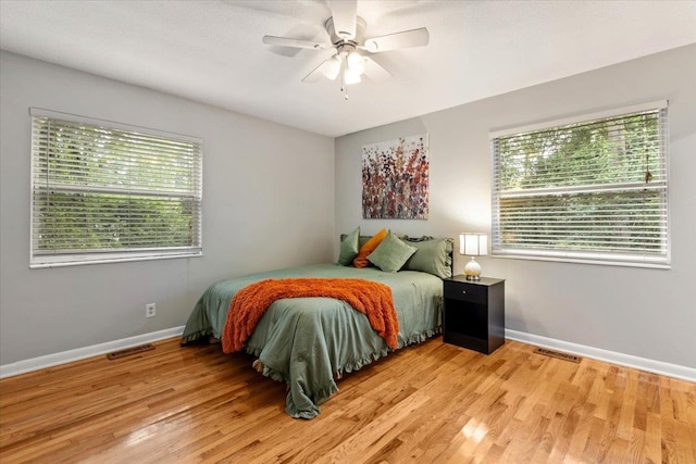 bedroom with ceiling fan, light hardwood / wood-style flooring, and multiple windows