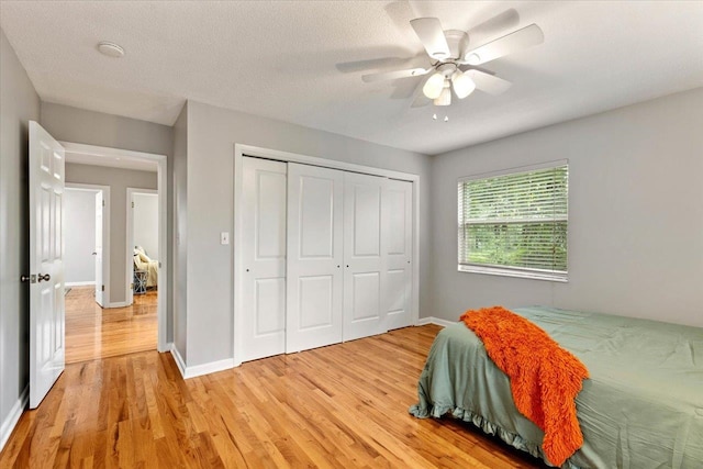 bedroom featuring a textured ceiling, a closet, light hardwood / wood-style floors, and ceiling fan