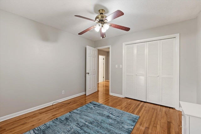 bedroom with a textured ceiling, a closet, hardwood / wood-style flooring, and ceiling fan