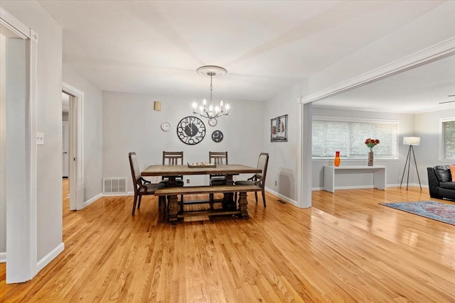 dining space featuring light wood-type flooring and an inviting chandelier