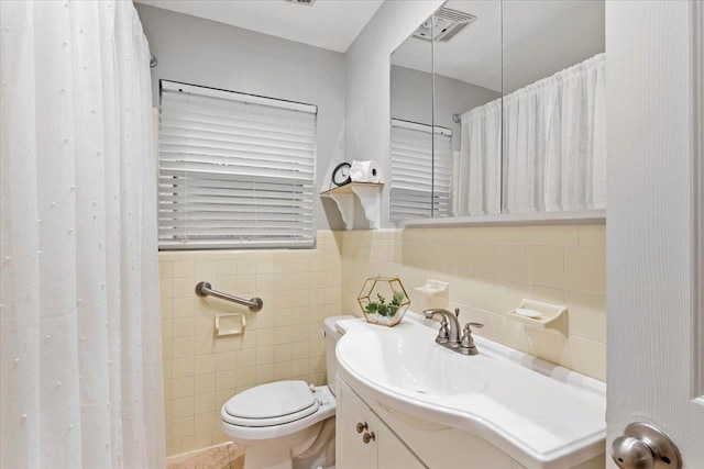 bathroom featuring vanity, toilet, and tile walls