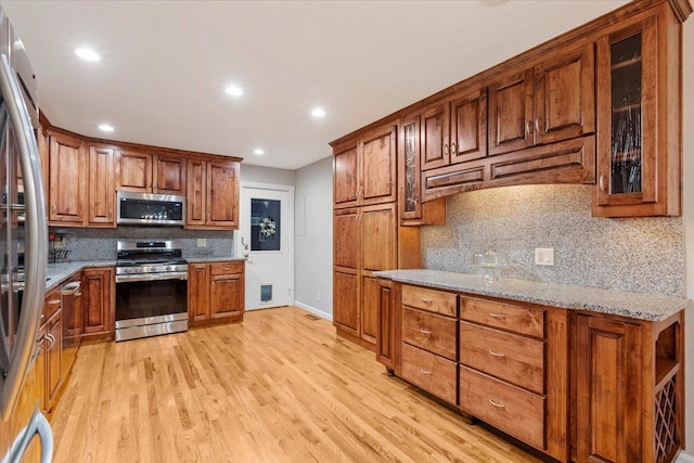 kitchen with light stone countertops, light hardwood / wood-style floors, and appliances with stainless steel finishes