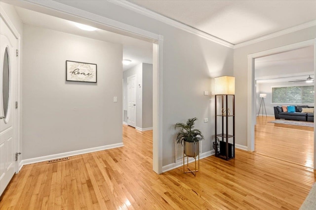 hall with crown molding and light hardwood / wood-style flooring