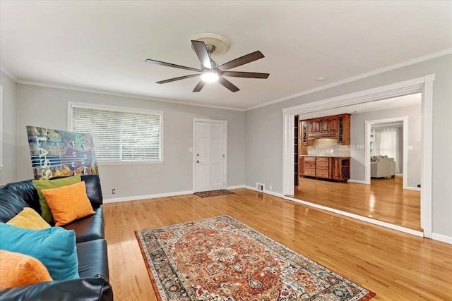 living room with light hardwood / wood-style flooring, ceiling fan, and ornamental molding