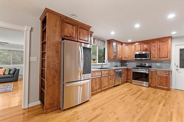 kitchen with decorative backsplash, appliances with stainless steel finishes, light hardwood / wood-style floors, and sink