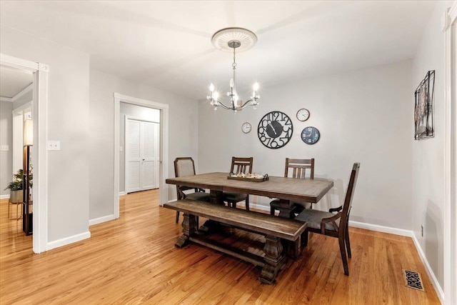 dining space with light hardwood / wood-style flooring and a chandelier