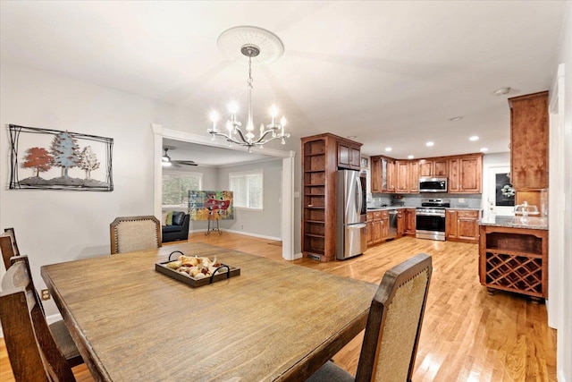 dining room with light hardwood / wood-style floors and ceiling fan with notable chandelier