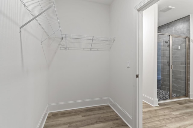 walk in closet with wood finished floors