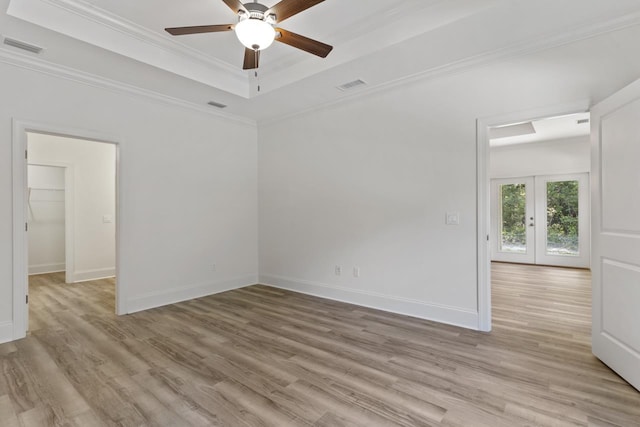 unfurnished room with ornamental molding, a raised ceiling, visible vents, and light wood finished floors