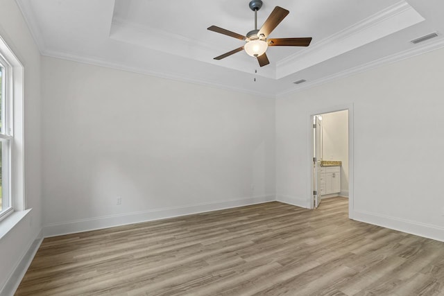 unfurnished room with ornamental molding, light wood-type flooring, a raised ceiling, and visible vents