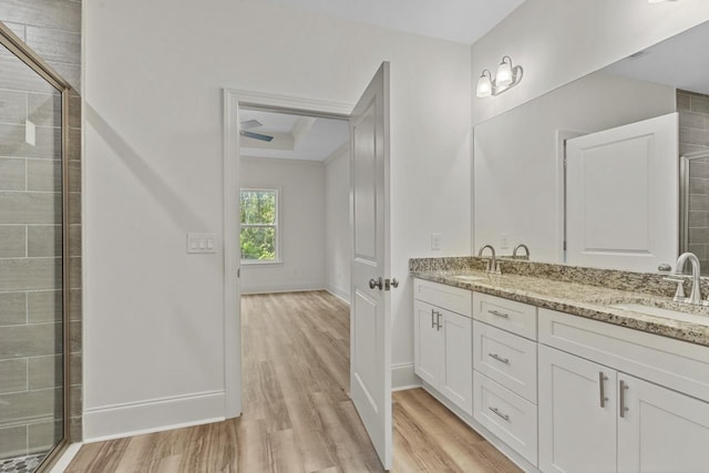 full bath with double vanity, wood finished floors, a sink, and baseboards