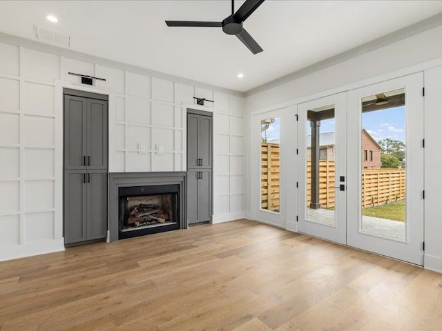 unfurnished living room featuring ceiling fan, built in features, light hardwood / wood-style floors, and ornamental molding