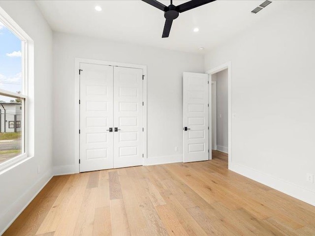 unfurnished bedroom featuring a closet, light hardwood / wood-style flooring, and ceiling fan