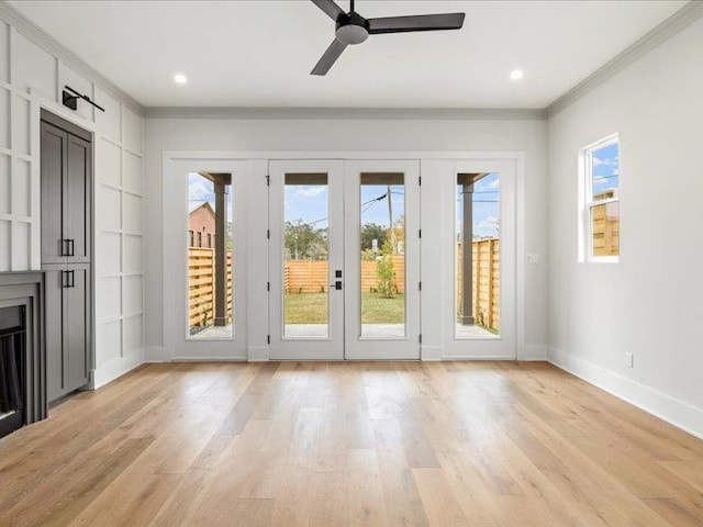 doorway featuring ornamental molding, a wealth of natural light, and light hardwood / wood-style flooring