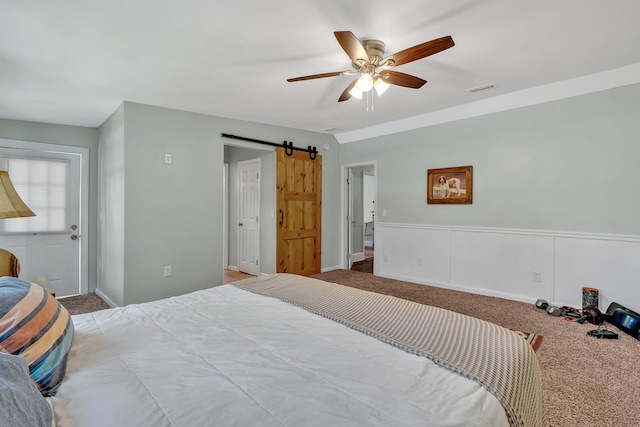 carpeted bedroom with ceiling fan and a barn door