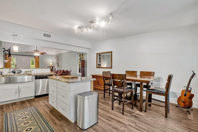 kitchen with a kitchen island, pendant lighting, sink, white cabinets, and stainless steel dishwasher