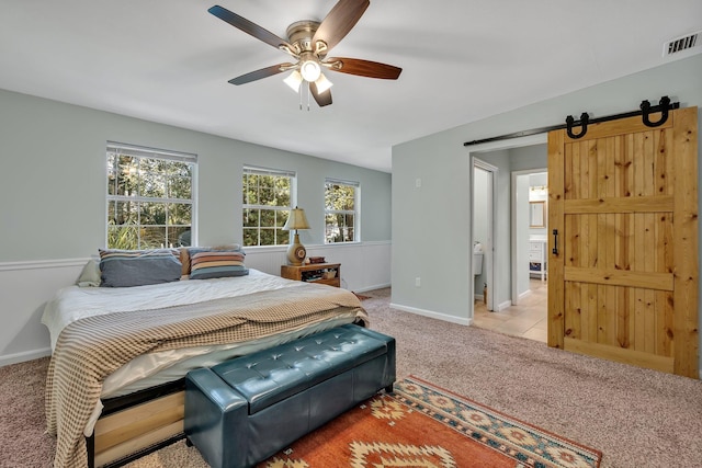 carpeted bedroom with a barn door and ceiling fan