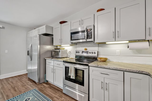 kitchen featuring light stone countertops, dark hardwood / wood-style floors, white cabinets, and appliances with stainless steel finishes