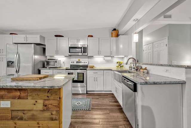 kitchen featuring stainless steel appliances, white cabinetry, light stone countertops, and pendant lighting