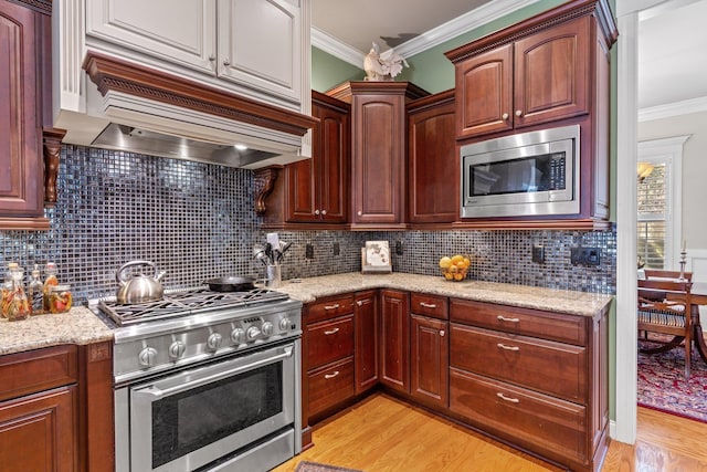 kitchen featuring custom exhaust hood, crown molding, light stone counters, light hardwood / wood-style flooring, and appliances with stainless steel finishes