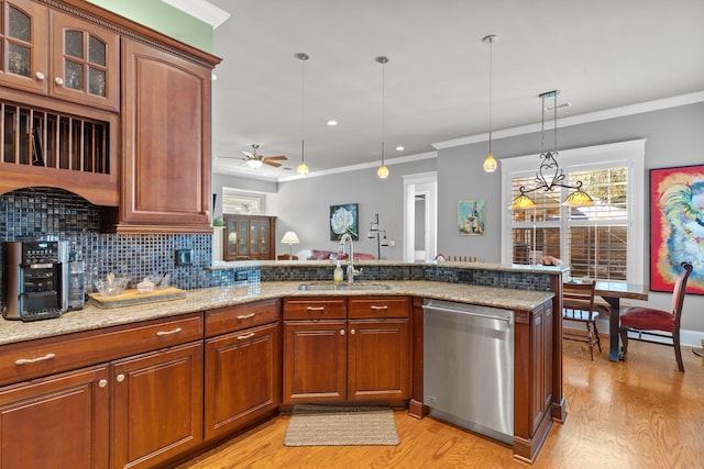 kitchen with sink, stainless steel dishwasher, pendant lighting, light stone countertops, and backsplash