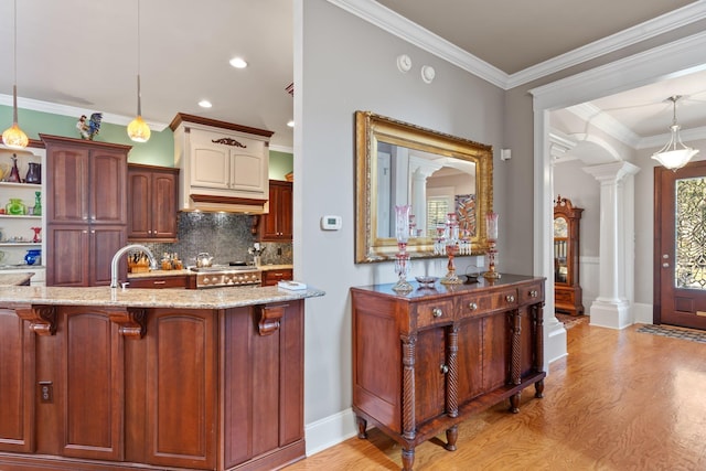 kitchen featuring ornate columns, crown molding, light hardwood / wood-style flooring, pendant lighting, and backsplash