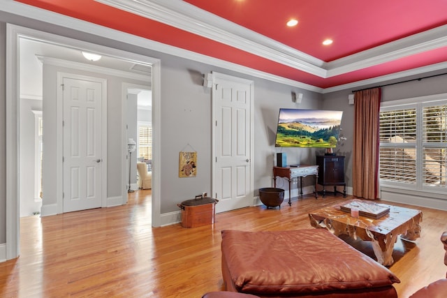 living room featuring ornamental molding, a tray ceiling, light hardwood / wood-style flooring, and a wealth of natural light