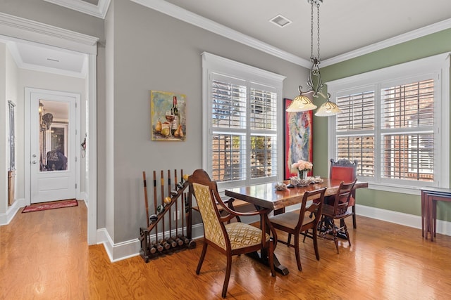 dining space with hardwood / wood-style floors, ornamental molding, and a healthy amount of sunlight