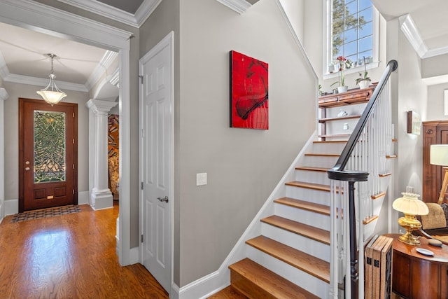 entrance foyer featuring decorative columns, crown molding, and hardwood / wood-style floors