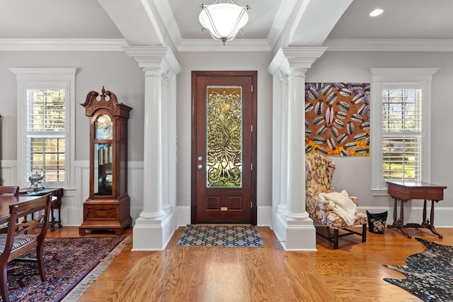 entrance foyer featuring crown molding, decorative columns, and light hardwood / wood-style floors