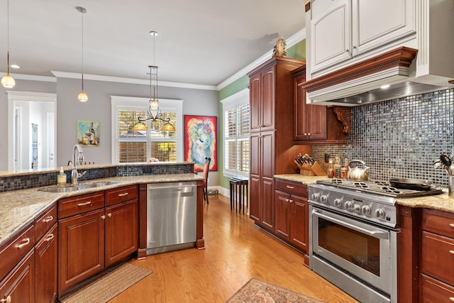 kitchen featuring premium range hood, sink, hanging light fixtures, ornamental molding, and stainless steel appliances