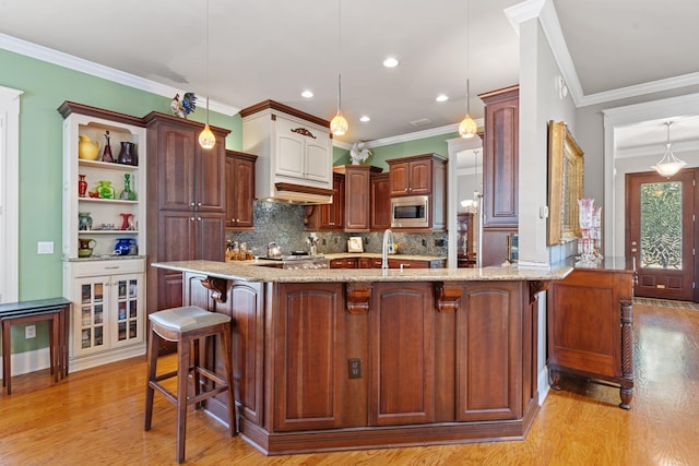 kitchen with a breakfast bar, stainless steel microwave, kitchen peninsula, pendant lighting, and light stone countertops