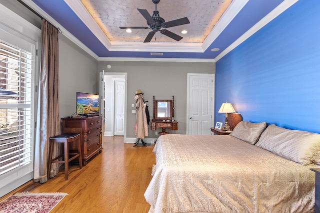 bedroom featuring crown molding, ceiling fan, a raised ceiling, and light hardwood / wood-style floors