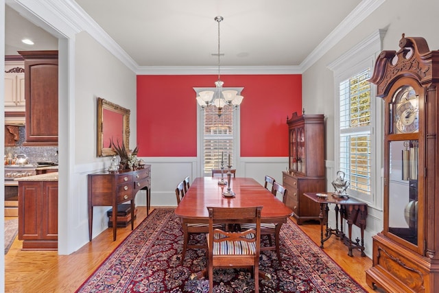 dining area featuring an inviting chandelier, ornamental molding, and light hardwood / wood-style floors