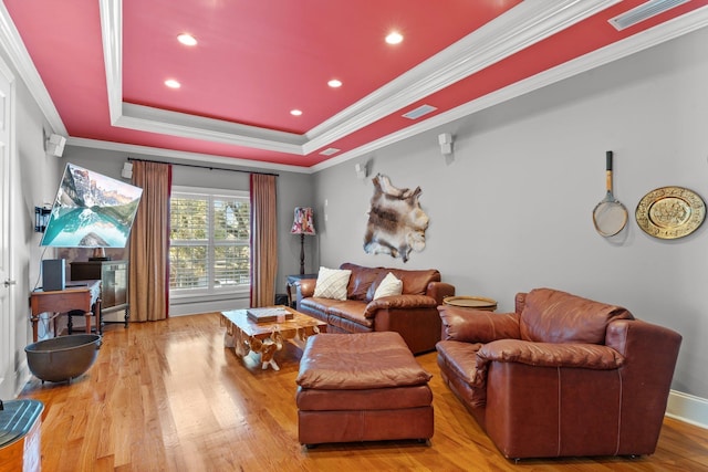 living room featuring crown molding, light hardwood / wood-style floors, and a tray ceiling